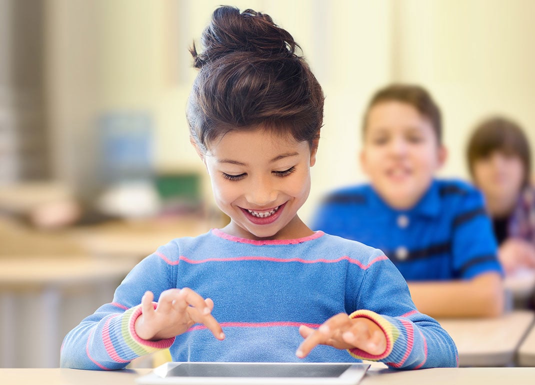 child-smiling-at-tablet-on-desk